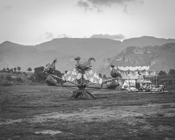 Scenic view of field against sky with roller-coaster 