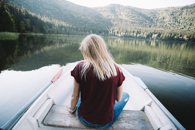 Rear view of woman sitting on boat at lake