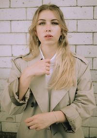 Portrait of woman standing against brick wall