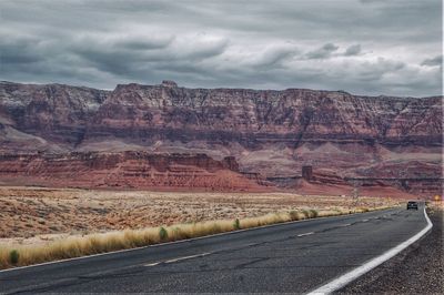 Road leading towards mountains against sky