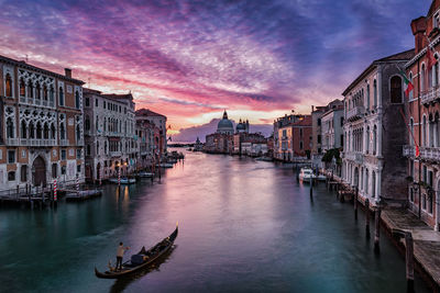 High angle view of man on gondola sailing in grand canal amidst buildings at sunset