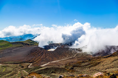 Smoke emitting from volcanic landscape against sky