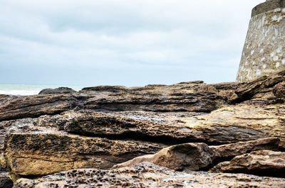 Rock formation on beach against sky