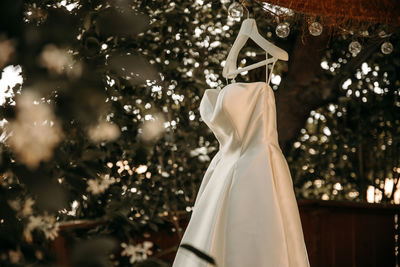 Beautiful wedding dress with pleats and tail hanging on white hanger outdoors. ballgown 