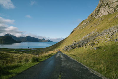 Road leading towards mountains against sky