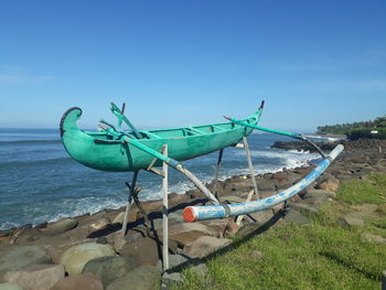 Fishing boat on beach against blue sky