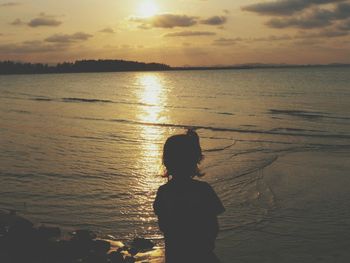 Silhouette woman standing by sea against sky during sunset