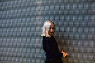 Portrait of woman standing against wall