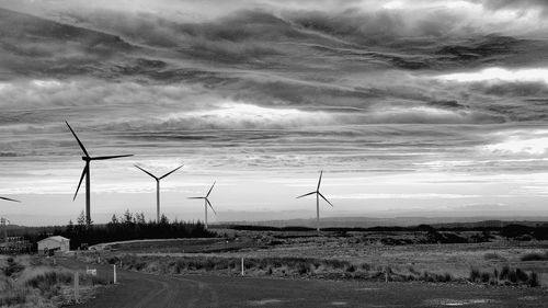 Wind turbines on field against sky