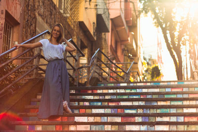 Portrait of young woman standing against building