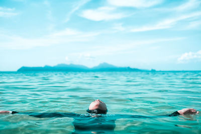 Teenage girl swimming in sea against sky