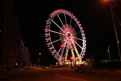 Low angle view of illuminated ferris wheel against sky at night