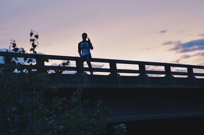 Low angle view of woman standing on bridge