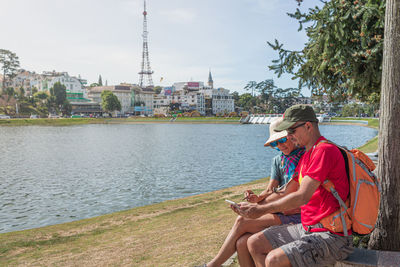 Man sitting on mobile phone against sky