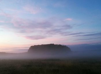 Scenic view of field against sky during sunset on foggy weather