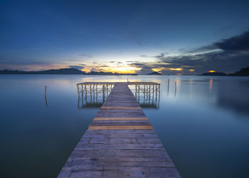 Pier over lake against sky during sunset