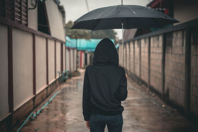 Rear view of man walking on wet street