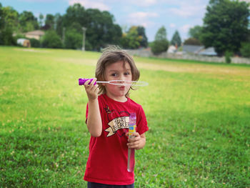 Young woman blowing bubbles on field