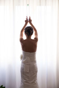 Rear view of bride opening curtain