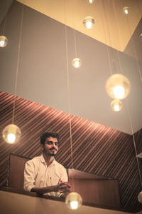 Low angle view of man sitting in illuminated lights