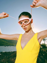 Portrait of young woman with arms raised standing at beach