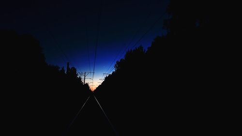 Low angle view of silhouette electricity pylon against sky at sunset