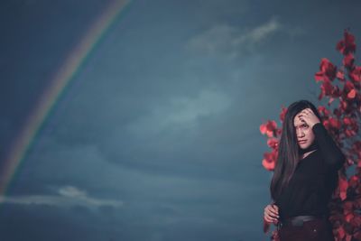 Full length of woman standing against rainbow in sky