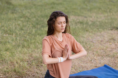 Woman with curly hair meditates in a park. yoga and meditation for mental and physical health