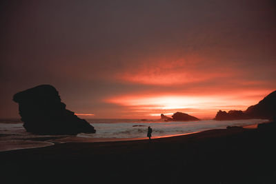 Silhouette people walking at beach against sky during sunset