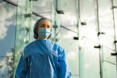 Low angle view of doctor wearing mask looking away