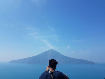 Rear view of man on mountain against sky