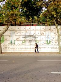 Full length of man walking on footpath in city