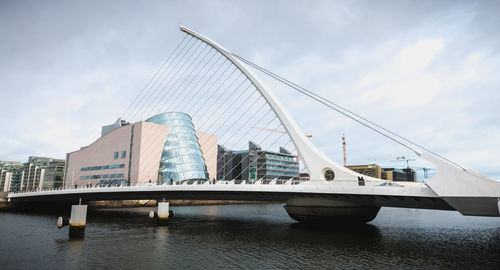 Bridge over river against sky in city