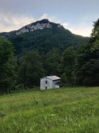 Built structure on field by mountain against sky