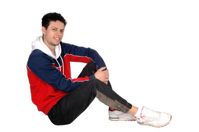 Portrait of young man sitting against white background