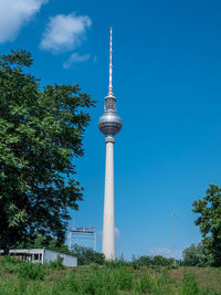 Communications tower in city against blue sky