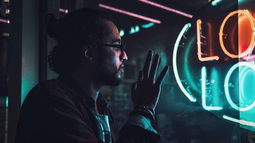 Close-up of thoughtful man looking through window at night