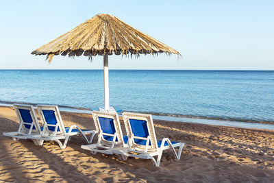 Deck chairs on beach against sky