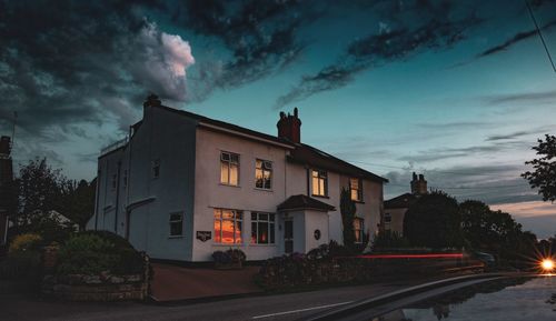 Cars on road by buildings against sky at dusk