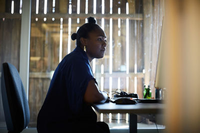 Side view of creative businesswoman working at computer desk in office