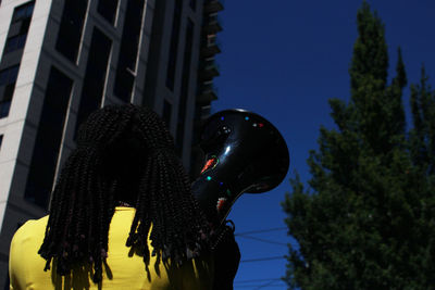 Side view of woman standing by tree against sky