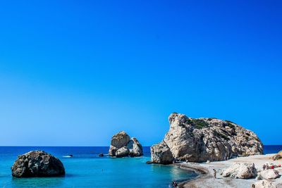 Rock formation in sea against clear blue sky