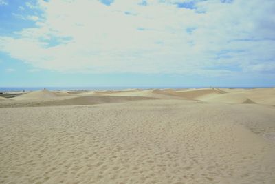 Scenic view of desert against cloudy sky