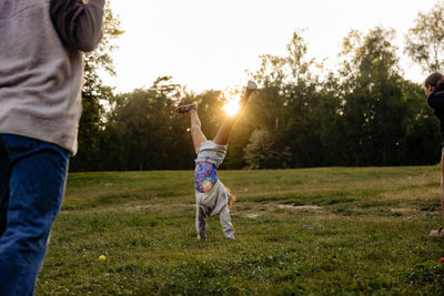 Girl practicing handstand on grass in playground at summer camp