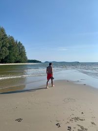 Rear view of woman on beach against sky