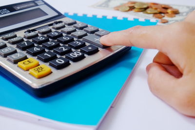 Cropped hand of person using calculator on table