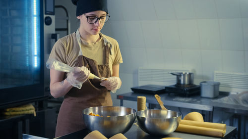Portrait of young woman preparing food in kitchen