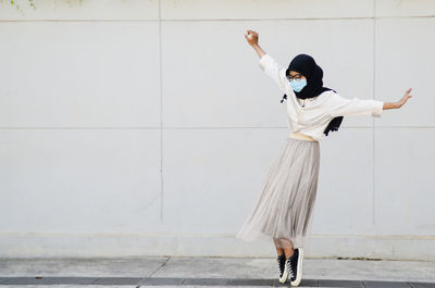 Full length of woman standing against white wall