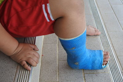 Low section of boy sitting on tiled floor