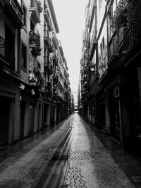 Empty alley amidst buildings in city against sky